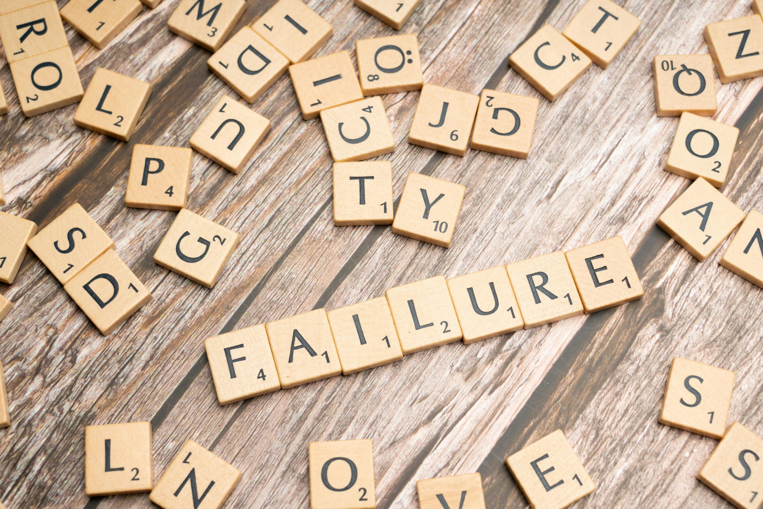 Wooden letter tiles spelling 'failure' on a wooden table, representing challenges.