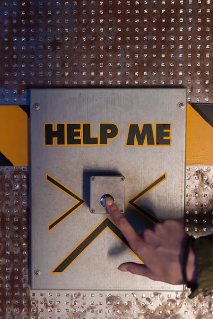 A hand presses an emergency 'help me' button on a metallic panel, evoking sci-fi themes.