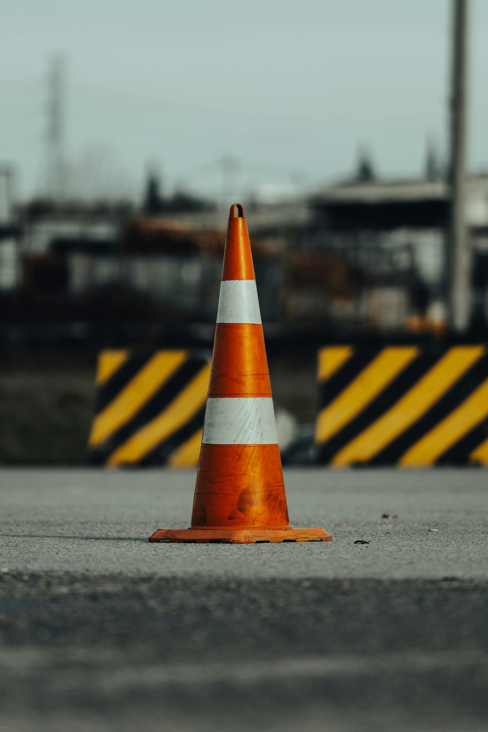 Close-up of an orange traffic cone on a city street, symbolizing road safety.